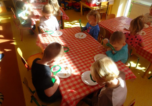 Dzieci oglądają przy użyciu lup różne nasiona i cebulki roślin.